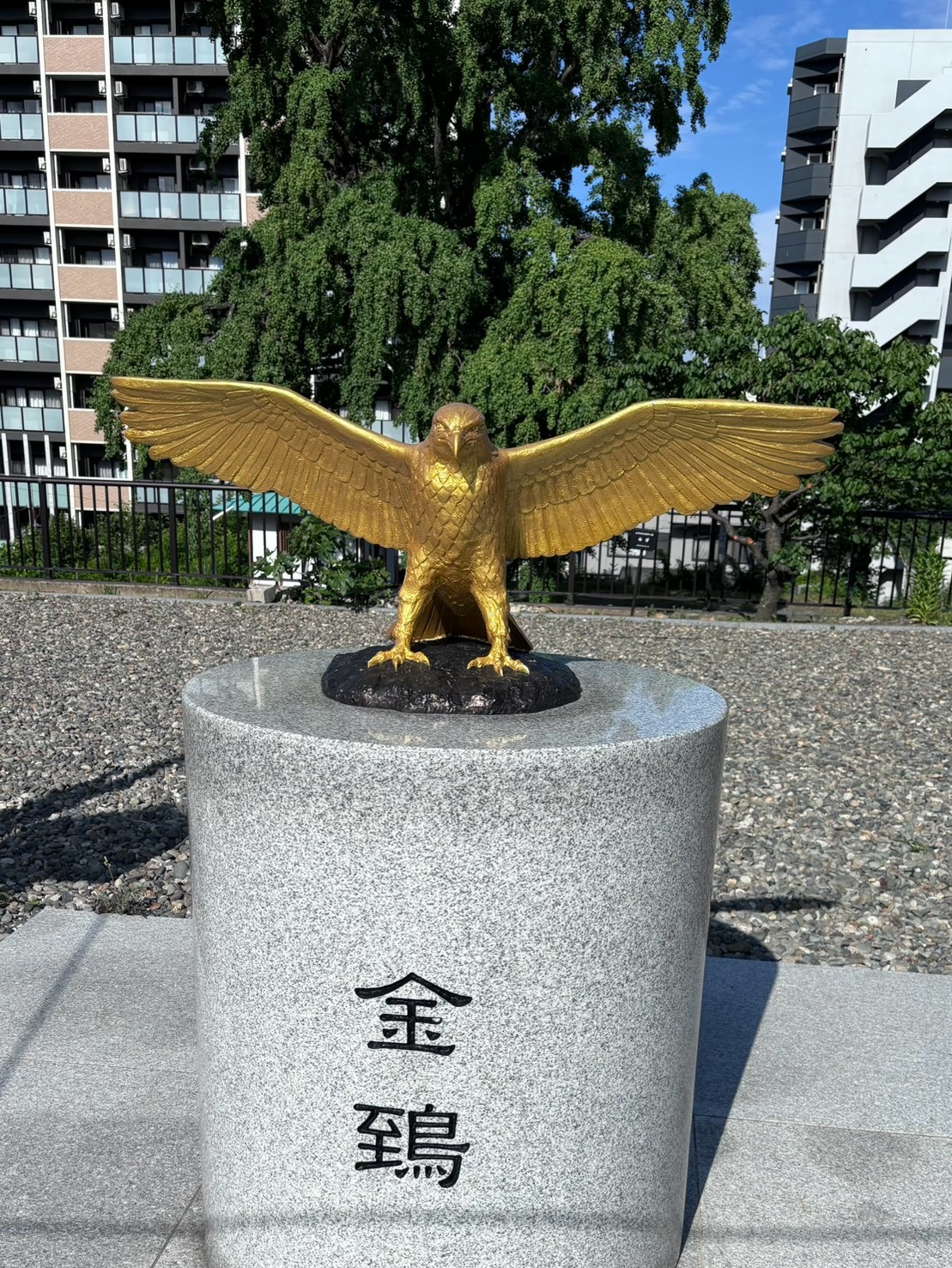 岡田宮の境内に立つ、金色に輝く金鵄（鳶）の銅像。台座に「金鵄」と刻まれている